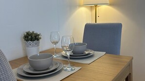 A dining table with plates, bowls, and wine glasses, a small potted plant, and a lamp. - Herring House -Only  2 minute walk  from the beach front . (Spittal)