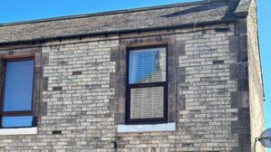 A two-story building with a brick facade, a green door, and multiple windows with blinds. - Herring House -Only  2 minute walk  from the beach front . (Spittal)