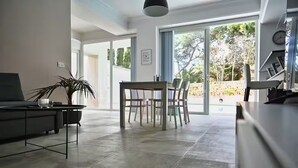 A modern living space with a dining area, a sofa, a coffee table, and a potted plant. - Villa Marni - Perfume (Munxar)
