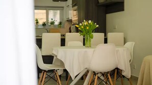 A dining area with a white table, chairs, and a vase of flowers. - Luzzu - Family Friendly Maisonette (Munxar)