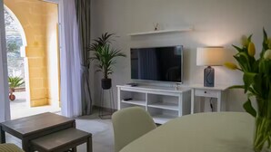 A modern living room with a TV, white console, and a dining area. - Luzzu - Family Friendly Maisonette (Munxar)