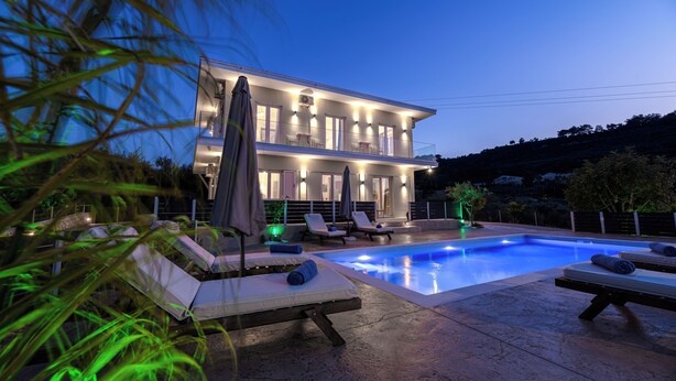 A two-story house with a swimming pool, lounge chairs, and umbrellas. - Athenia Apartments (Zakynthos)
