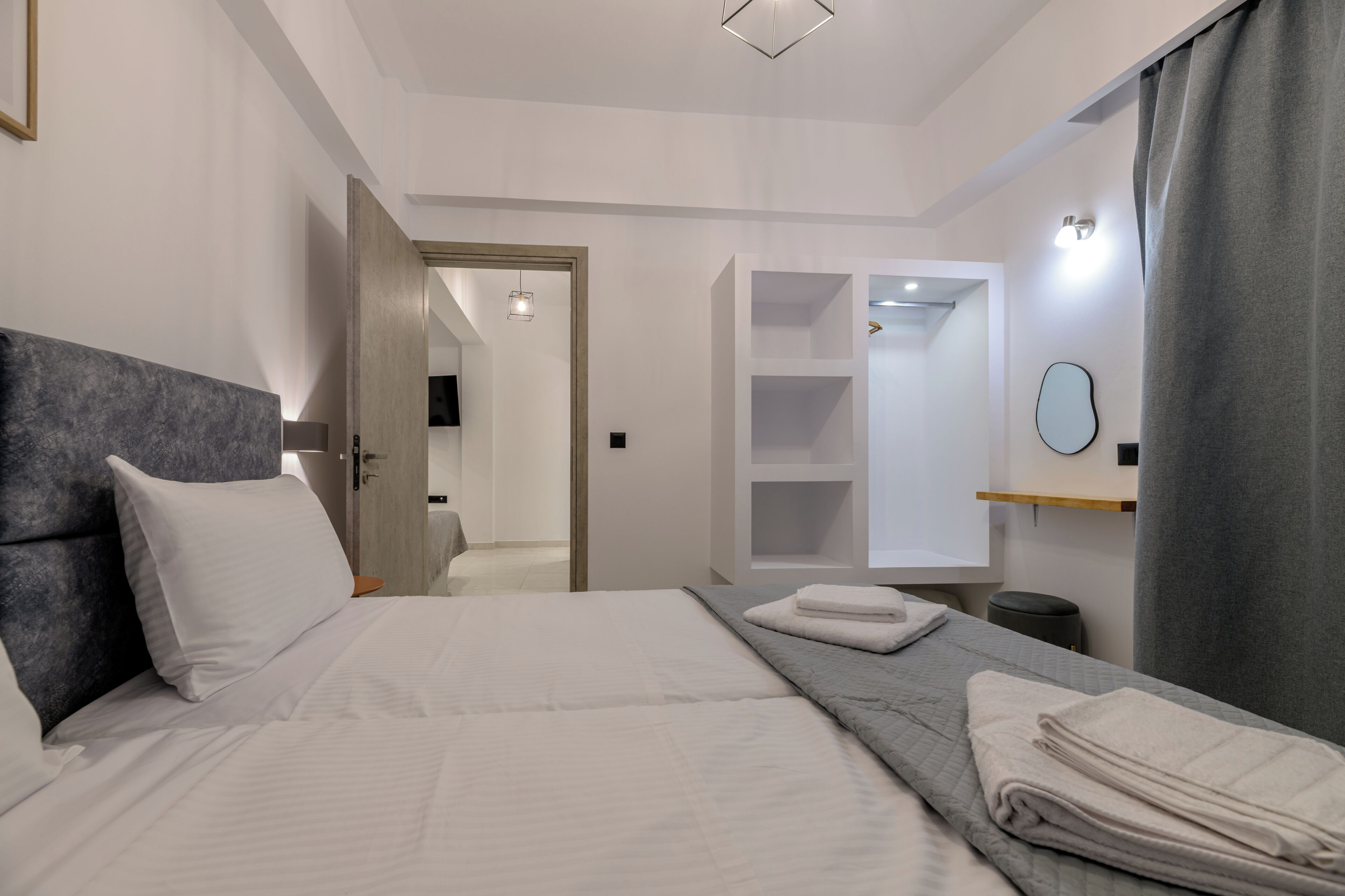 Une chambre d’hôtel moderne avec un grand lit, une table de chevet, un miroir et une armoire.