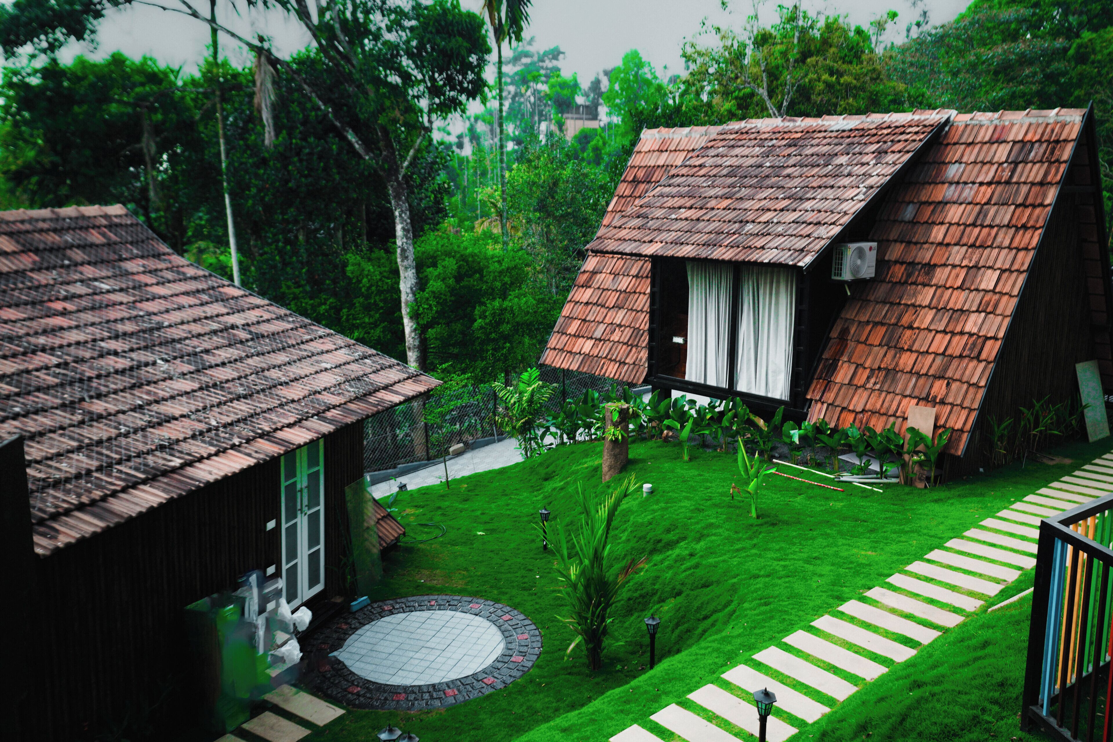 A traditional house with a tiled roof, a circular garden area, and a pathway leading to the entrance.