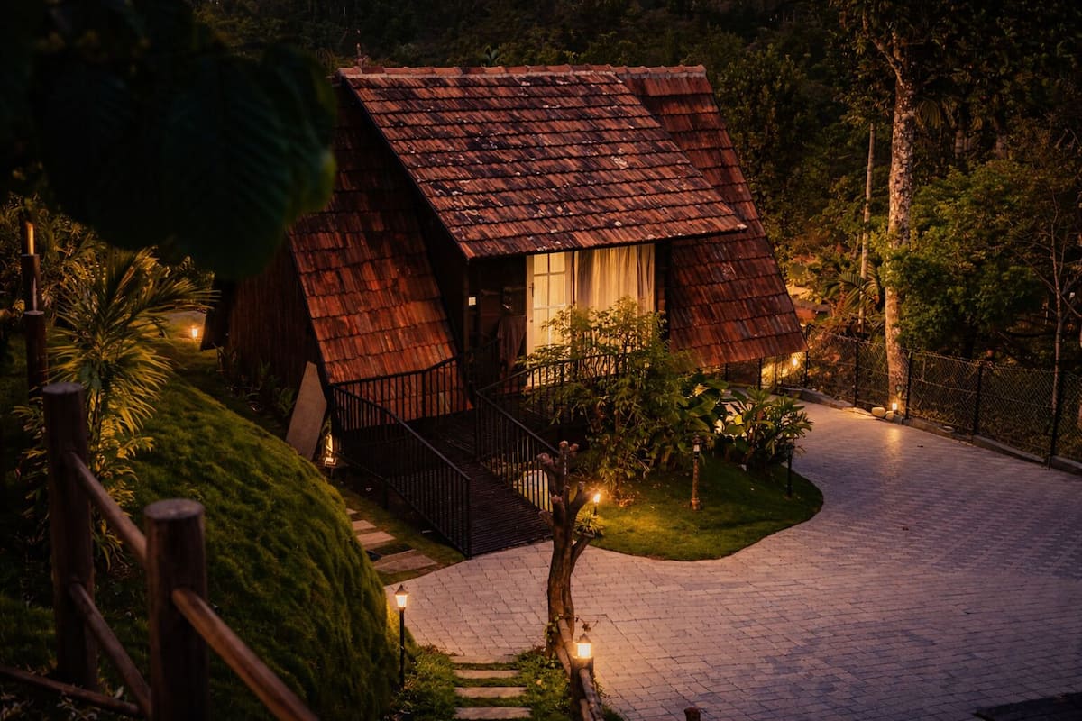 A rustic house with a sloped roof, a small porch, and a paved driveway.