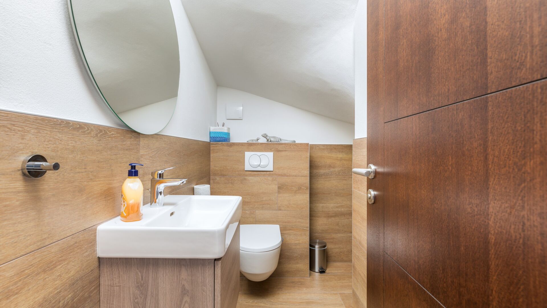 Un baño con un lavabo blanco, un inodoro y un mueble de tocador de madera.