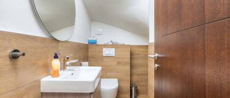 Un baño con un lavabo blanco, un inodoro y un mueble de tocador de madera.
