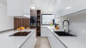 Een moderne keuken met witte aanrechtbladen, een zwart spoelgedeelte en een houten kastje.