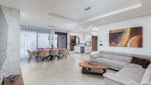 Een moderne woonkamer met een bank, salontafel en een eetgedeelte met stoelen.