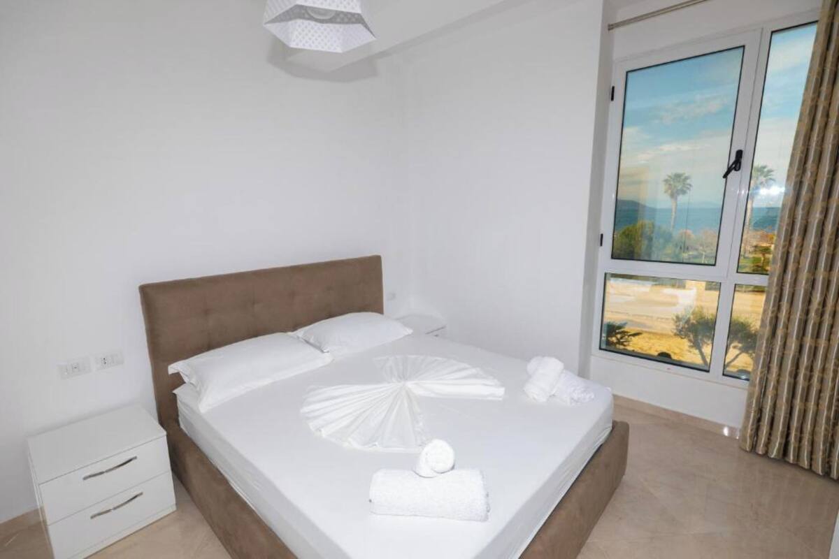 A hotel room with a bed, a nightstand, a window with a view, and a curtain.