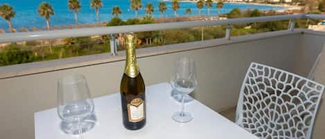 A balcony with a table, two wine glasses, and a bottle of wine.