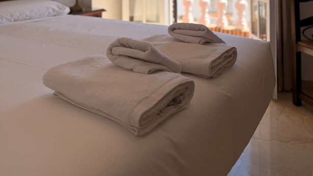 A hotel room with a bed, a nightstand, a lamp, and an open window with a view. - Hotel Victoria Matalascañas (Matalascañas)