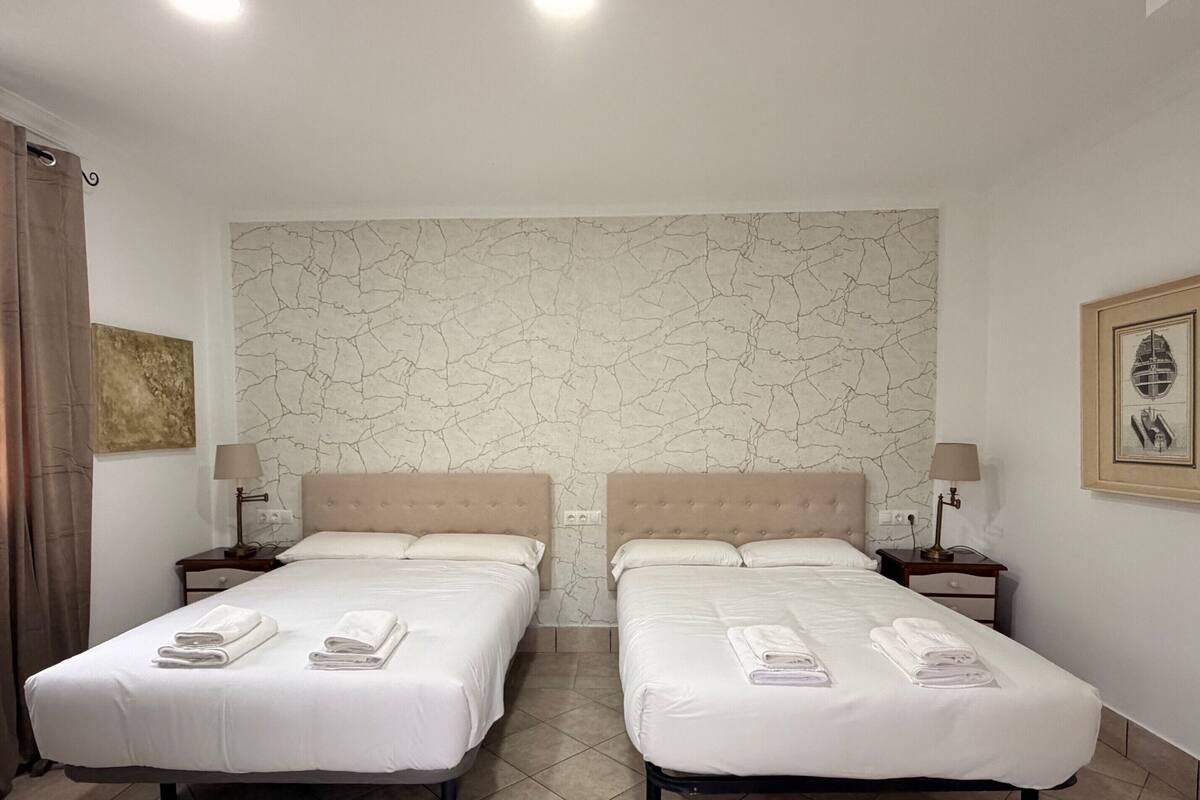 Habitación de hotel con dos camas, pared con diseño de mármol y un cuadro enmarcado.