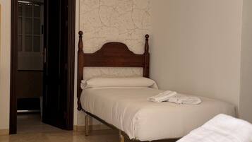 Un dormitorio con cama de madera, pared blanca con un diseño agrietado y una puerta que da a otra habitación.