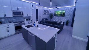 Una cocina moderna con una isla central, electrodomésticos integrados y una pared decorativa de piedra.