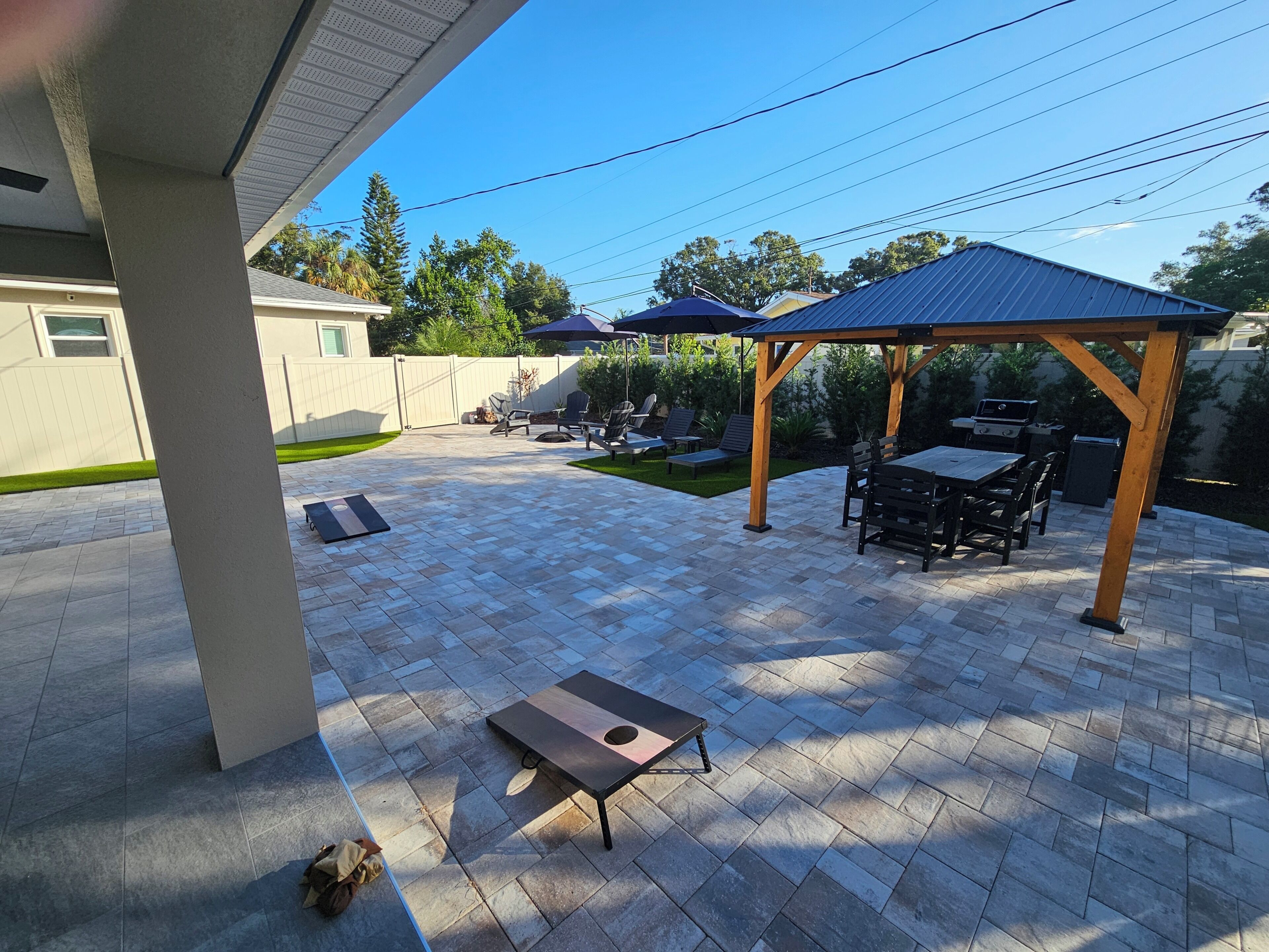 A patio with a pergola, outdoor seating, and a grill area.