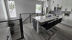 Una cocina moderna con una isla central, electrodomésticos de acero inoxidable y vistas al exterior.