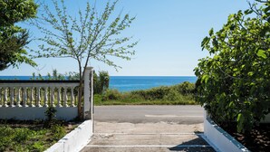 A paved pathway leading to a white gate with a view of the sea. - Serenity Apartments (Corfu)