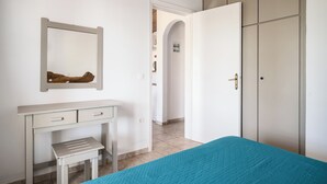 A bedroom with a bed, a desk, a wardrobe, and a mirror. - Serenity Apartments (Corfu)