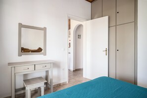 Ein Schlafzimmer mit Bett, Schreibtisch, Kleiderschrank und Spiegel.