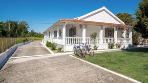 A white building with a red roof, a porch, and bicycles parked in front. - Serenity Apartments (Corfu)