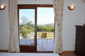 A room with a sliding glass door leading to an outdoor patio with chairs and a table. - Villa Miquela Charming house with ocean view (IB)