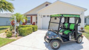 A golf cart parked in front of a single-story house with a garage.