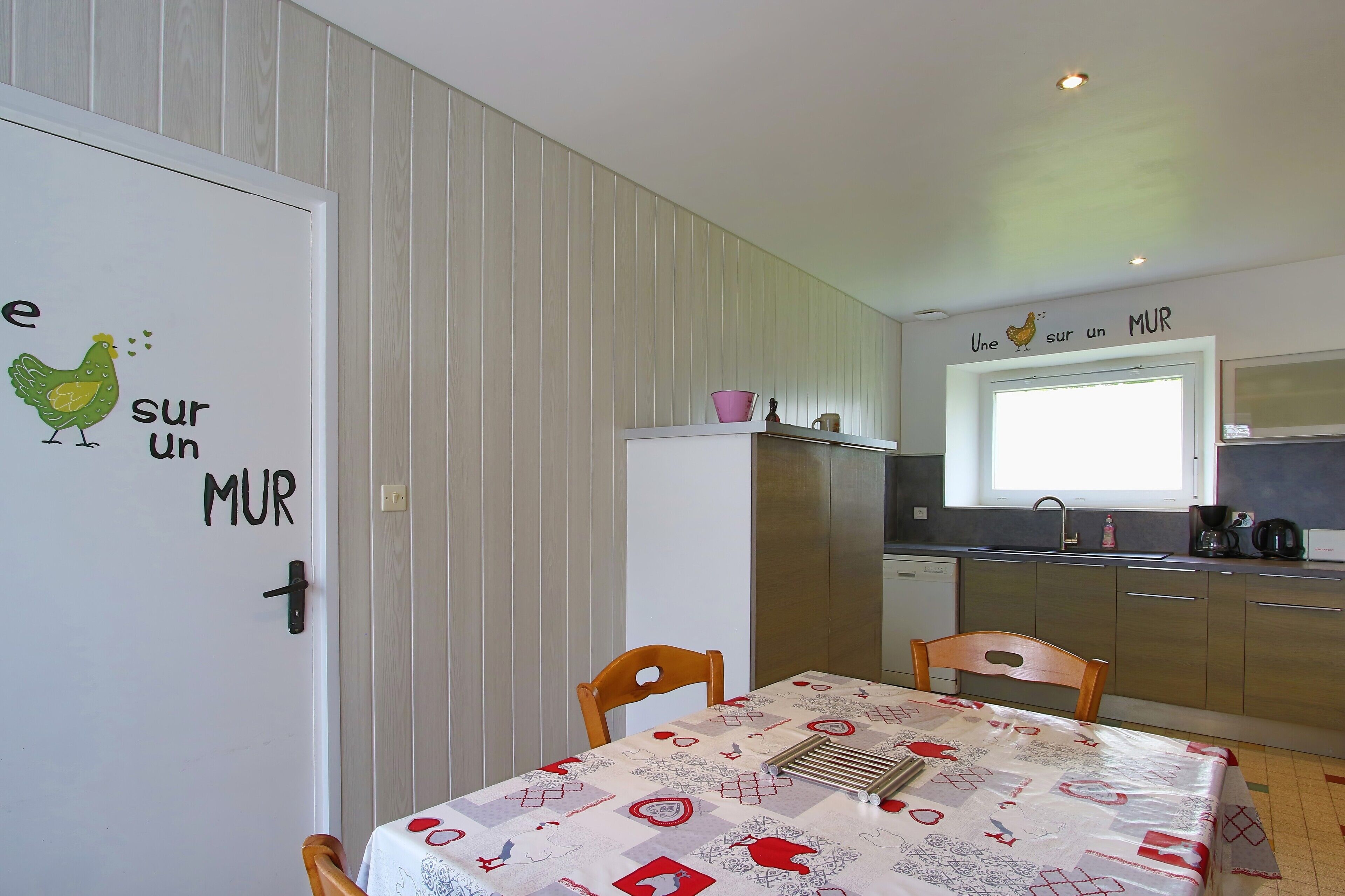 Ett kök med ett matbord, stolar och ett kylskåp.