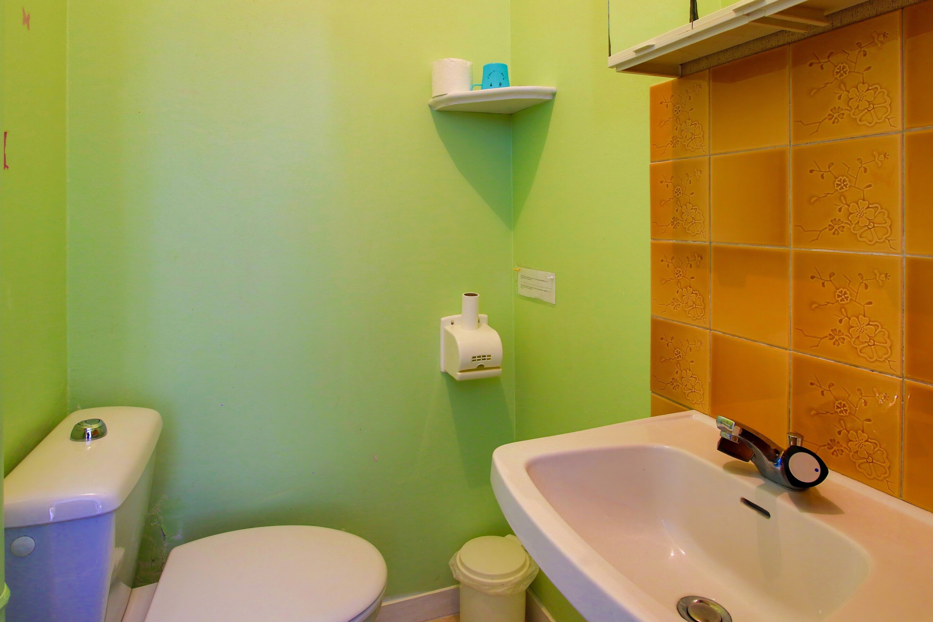 Een badkamer met toilet, wastafel en een plank met toiletartikelen.