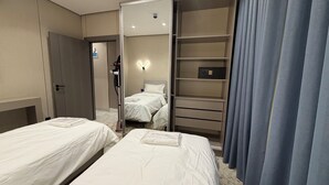 Camera d'albergo con due letti, un armadio, uno specchio e uno scaffale con una cassaforte.