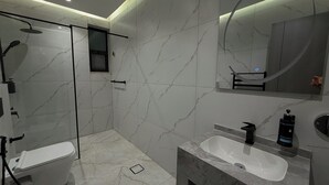 Un bagno moderno con doccia vetrata, lavandino bianco e uno specchio grande.
