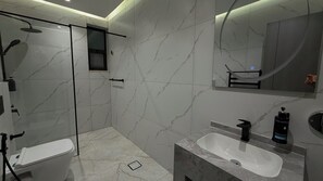 Ein modernes Badezimmer mit einer Duschkabine, einem weißen Waschbecken und einem großen Spiegel.