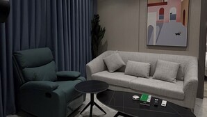 Un soggiorno moderno con un divano, una poltrona, un tavolino da caffè e un quadro appeso al muro.