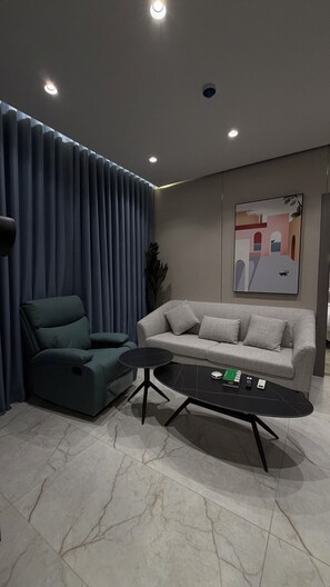 Ein modernes Wohnzimmer mit einer Couch, einem Sessel, einem Couchtisch und einem Gemälde an der Wand.