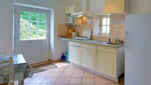 Una cocina con microondas, estufa, lavamanos y armarios.