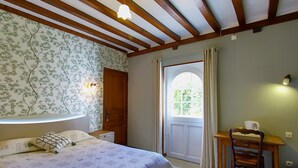 Un dormitorio con cama, escritorio, silla, ventana con cortinas y techo de madera.