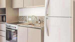 A kitchen with a built-in oven, a stainless steel refrigerator, and a granite countertop. - Deluxe Apartment en Recoleta by Magno | 3A (Buenos Aires)