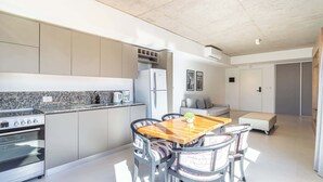 Une cuisine moderne dotée d’un four encastré, une table à manger avec des chaises et un canapé dans l’espace salon.