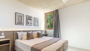 Une chambre à coucher moderne avec un grand lit, des tables de chevet et des œuvres d’art encadrées accrochées au mur.