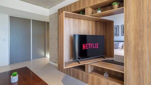 Un salon moderne avec un meuble de rangement en bois, un téléviseur à écran plat et une petite table sur laquelle est posée une plante.