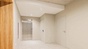 A hallway with a wooden bench, a door, and a lift. - Deluxe Apartment en Recoleta by Magno | 1A (Buenos Aires)