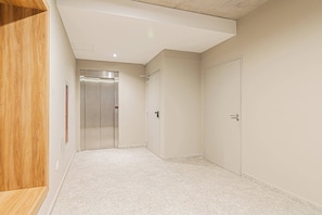 Un pasillo con un banco de madera, una puerta y un ascensor.
