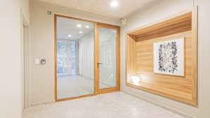 A hallway with a wooden door, a framed abstract artwork, and a tiled floor. - Deluxe Apartment en Recoleta by Magno | 1A (Buenos Aires)