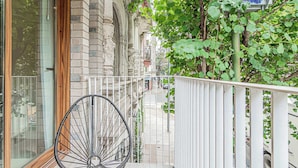 A balcony with a bicycle, a white railing, and a view of a street with parked cars. - Deluxe Apartment en Recoleta by Magno | 1A (Buenos Aires)