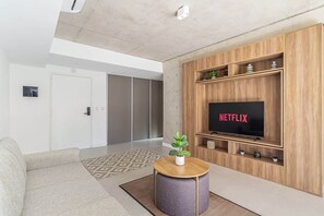 A modern living room with a sofa, a round coffee table, a television on a wooden stand, and a patterned rug. - Deluxe Apartment en Recoleta by Magno | 5A (Buenos Aires)