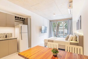 Cozinha compacta com geladeira, uma mesa de jantar com cadeiras, um sofá e uma janela com vista para o exterior.