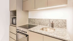 Eine moderne Küche mit Granit Arbeitsplatte, Edelstahlgeräten und beigen Schränken.