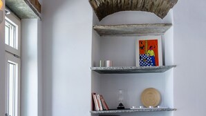 A room with a stone shelf, a sofa, a vase, and a framed picture. - Veggera Living, Tinos (Pyrgos)