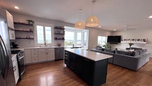 Een moderne keuken met een centraal eiland, houten vloeren en hanglampen.