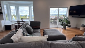 Een moderne woonkamer met een grijze modulaire bank, een eettafel en een grote televisie.